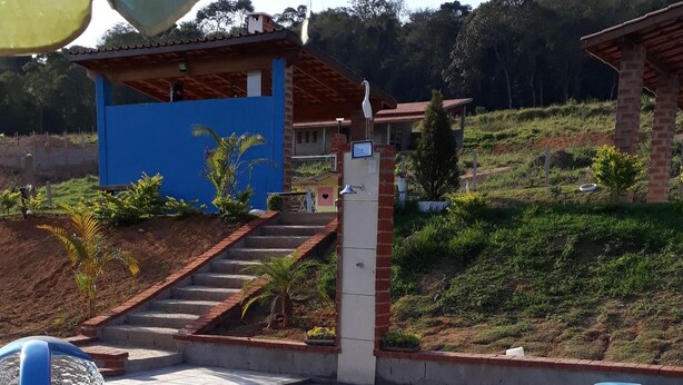 A swimming pool with a water fountain, surrounded by a tiled patio. - Mini Chácara Campo Verde Ibiúna SP<br>A cozy and simple place to relax (Ibiúna)
