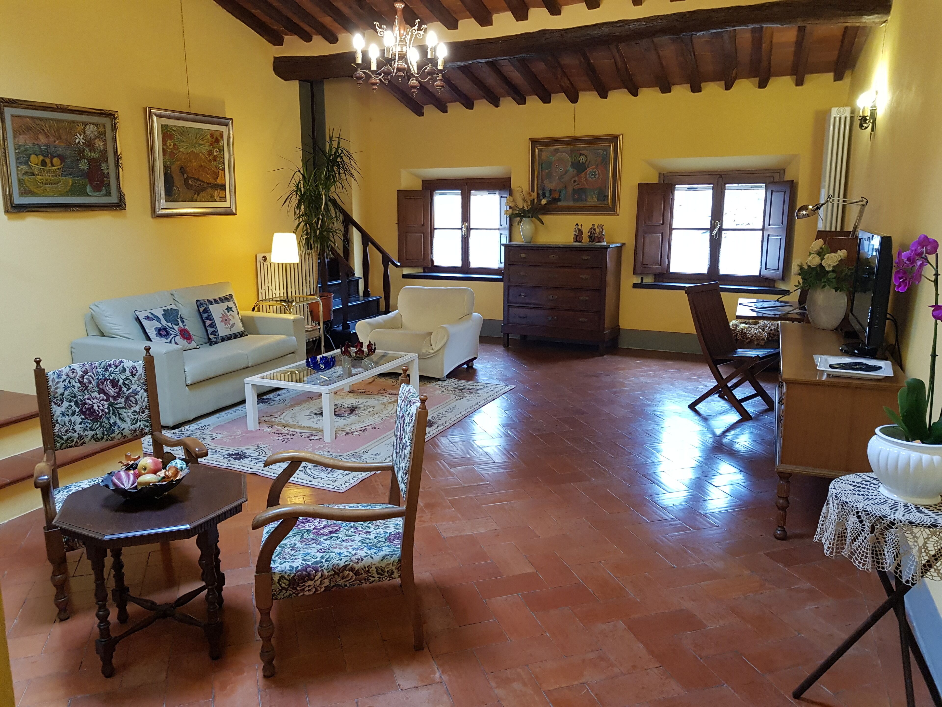 Amplia sala de estar con sofá, sillones, mesa de centro y comedor con mesa y sillas.