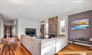 Ein modernes Wohnzimmer mit einem großen Ecksofa, einem Kamin und einem Bild an der Wand.