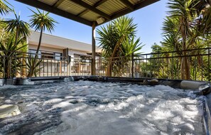 Un espace avec un jacuzzi offrant une vue sur un immeuble et des palmiers.