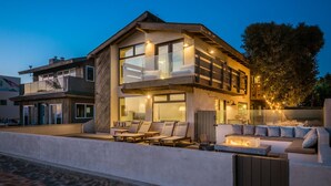 Une maison moderne à deux étages dotée d’un balcon, d’un espace extérieur aménagé pour se détendre et d’un foyer.