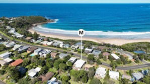 An aerial view of a coastal residential area with houses, a beach, and a road. - Mitchellmook in Mollymook (Mollymook Beach)