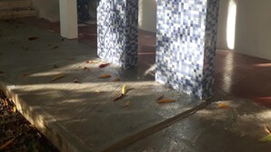 Una entrada con suelo de baldosas y suelo de hormigón, con una ventana a la izquierda.