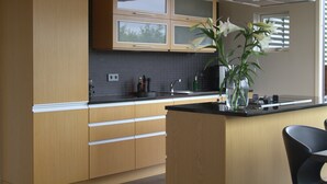 A modern kitchen with wooden cabinets, a black countertop, and a vase with white flowers. - Luxury cottage, Golden  Circle. HG-00004618 (Grímsnes- og Grafningshreppur)
