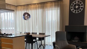 A modern living room with a dining area, a fireplace, and a kitchen with a wooden island. - Luxury cottage, Golden  Circle. HG-00004618 (Grímsnes- og Grafningshreppur)