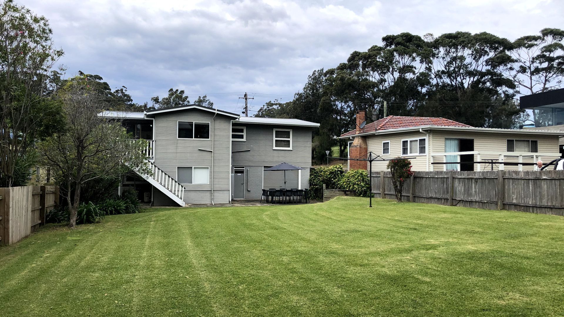 A two-story house with a fenced backyard, a patio with outdoor furniture, and a visible satellite dish.