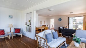 A spacious living area with a dining table, sofas, and a kitchen in the background. - Surf & Turf Retreat in Mollymook (Mollymook)