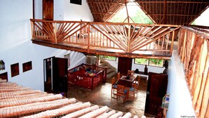 Une pièce spacieuse avec un plafond haut, un escalier en bois et un coin repas comprenant des chaises et une table.