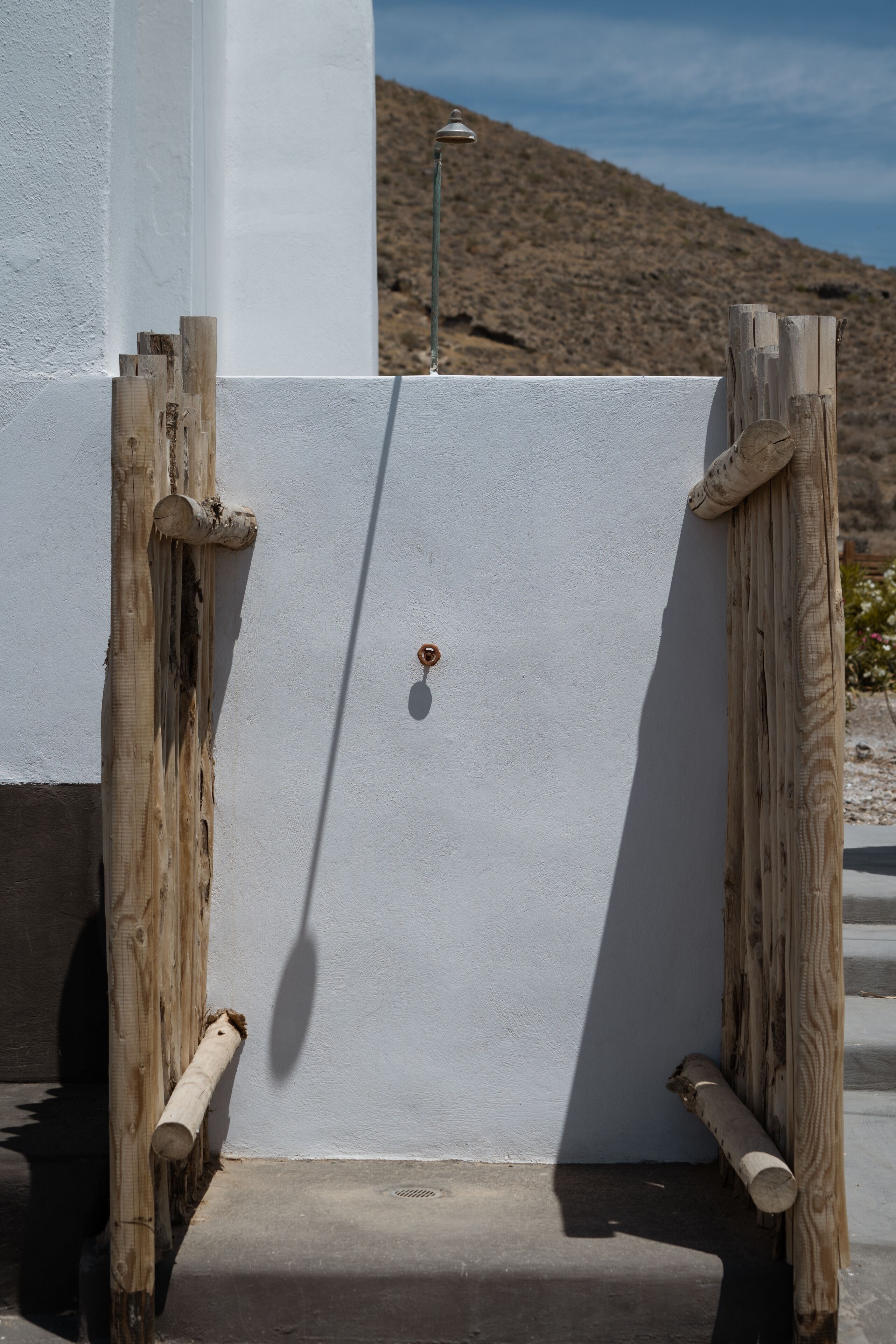 A white door with a metal handle, flanked by wooden posts, set against a desert landscape.
