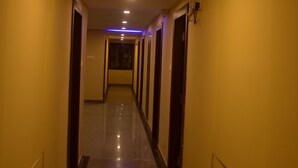 Um corredor de hotel longo, com portas em ambos os lados e uma luminária no teto.