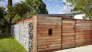 A wooden structure with a stone wall, a small black box, and a grassy area. - Cuballa - Just a few minutes flat  walk to town & the river .Modern clean house (Bright)