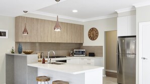 A modern kitchen with a central island, stainless steel appliances, pendant lighting, and a clock on the wall. - Cuballa - Just a few minutes flat  walk to town & the river .Modern clean house (Bright)