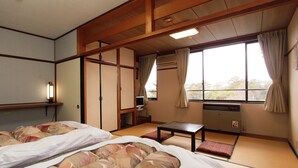 A traditional Japanese-style room with tatami flooring, a futon bed, a small table, and sliding doors. - Kokumin Shukusha Enasansou (Ena)