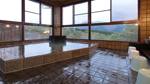 A hot spring bath area with a view of mountains through large windows. - Kokumin Shukusha Enasansou (Ena)