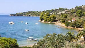 A coastal area with boats on the water, a beach, and houses on a hillside.