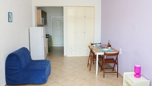 A compact living space with a kitchenette, a dining area, and a blue sofa.