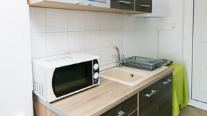 A kitchen with a microwave, sink, and a dish rack.