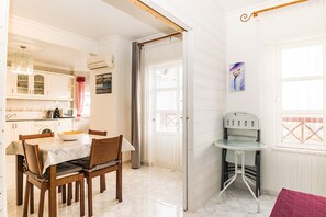 Un comedor con una mesa y sillas, una cocina al fondo y una ventana con vistas.