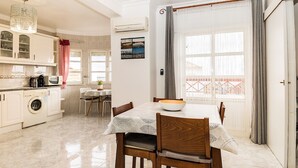 A well-lit kitchen with a dining area, a washing machine, and a table set for two.