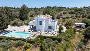 Une villa à deux étages dotée d’une piscine, de chaises longues et d’un espace salon extérieur couvert.