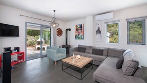 Un salon moderne avec un canapé gris, un fauteuil bleu, une table basse en bois, un téléviseur à écran plat et une cheminée.