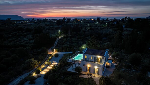 Une maison moderne dotée d’une piscine, entourée d’un jardin aménagé et bordée d’un sentier sinueux.