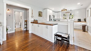 Cucina spaziosa con mobili bianchi, un piano di lavoro in legno e un'isola integrata.
