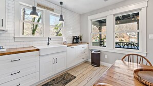 Una cucina moderna con mobili bianchi, un piano di lavoro in legno e un'ampia finestra vista all'esterno.