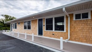 A single-story building with a brick facade, white trim, and a covered porch with white railings. - Peaceful Condo for Cozy Cape Getaway (Provincetown)