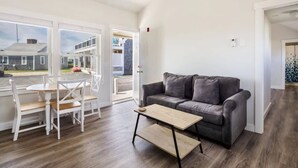 A modern living room with a grey sofa, wooden coffee table, and white chairs. - Peaceful Condo for Cozy Cape Getaway (Provincetown)