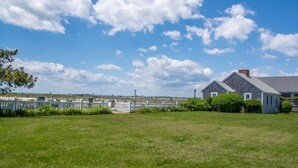 A house with a fenced yard and a clear sky. - Peaceful Condo for Cozy Cape Getaway (Provincetown)