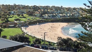 A coastal town with a sandy beach, residential buildings, and a clear sky. - Ocean View Apartment with a Stroll to Bronte Beach (Bronte)