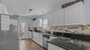 Eine moderne Küche mit weißen Schränken, einer schwarzen Granit Arbeitsplatte und einer Spritzschutzleiste mit farbenfrohen Fliesen.