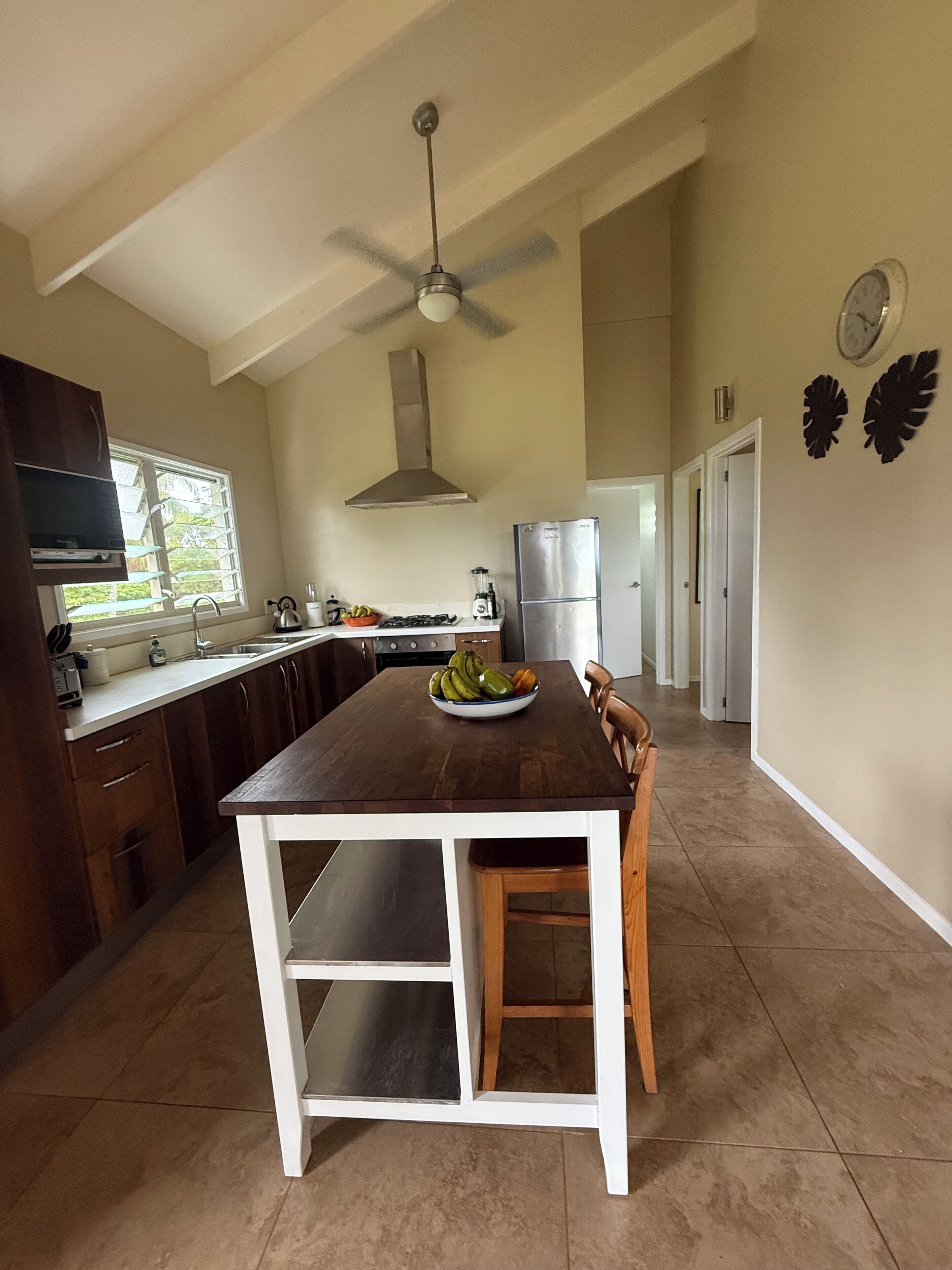 Una cocina con una mesa de comedor, ventilador de techo, refrigerador y una ventana.