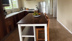 Uma cozinha com mesa de jantar, ventilador de teto, geladeira e janela.