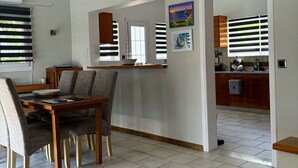 A dining area with a wooden table and chairs, a kitchen with wooden cabinets, and a tiled floor. - LAZAROS villa in Agios Matheos Corfu  (AGIOS MATHEOS CORFU)