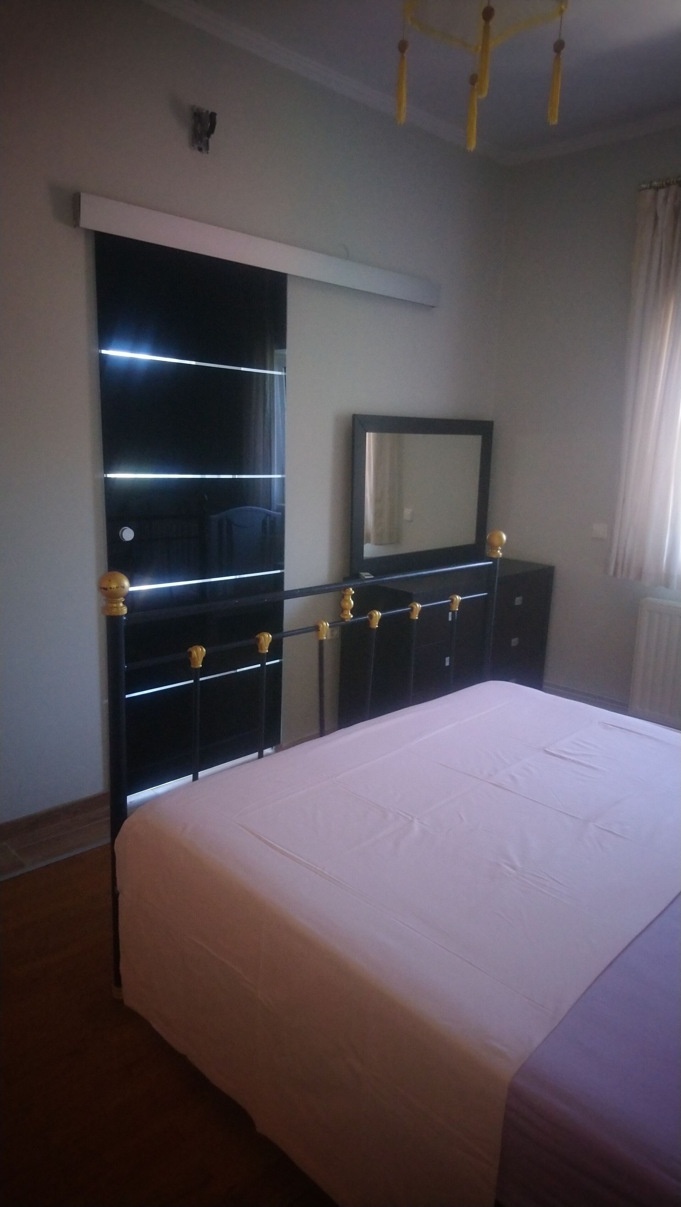 Een slaapkamer met een bed, een kledingkast, een spiegel en een plafondlamp.