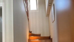A wooden staircase with a handrail, a small window at the top, and a door at the bottom. - LAZAROS villa in Agios Matheos Corfu  (AGIOS MATHEOS CORFU)