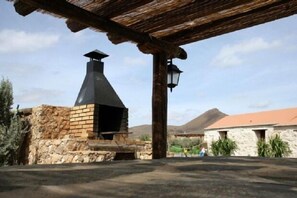 A stone building with a chimney, a wooden pergola, and a stone wall.