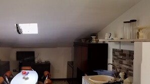 Un pasillo estrecho con una lámpara en el techo, una puerta que da a una habitación y una zona de cocina con un fregadero y armarios.