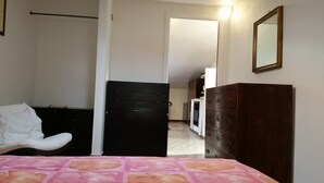 Un dormitorio con cama, armario, cómoda y espejo.