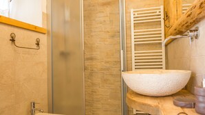 Een badkamer met een douchecabine van glas, een witte wastafel en een bidet.