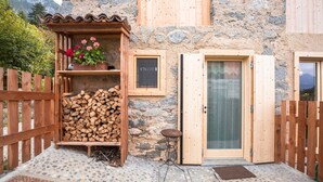 Een rustieke houten hut met een stenen muur, een houten deur en een klein houten tafeltje.