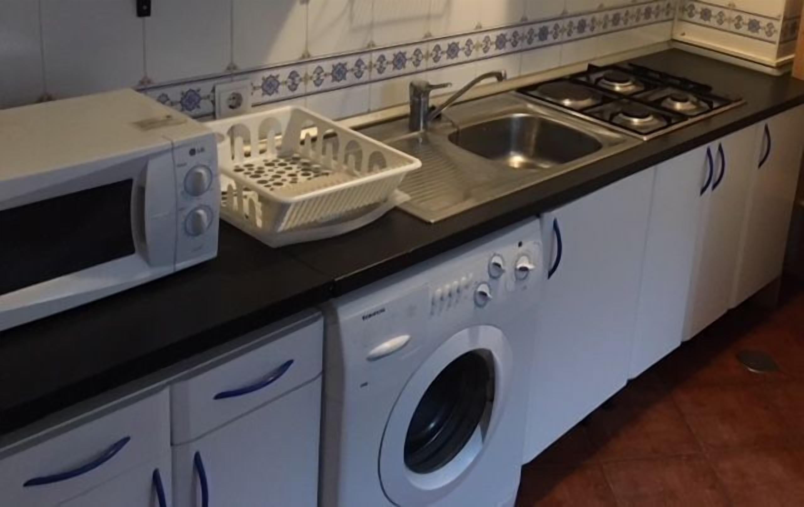 A compact kitchen with a microwave, sink, and stove.