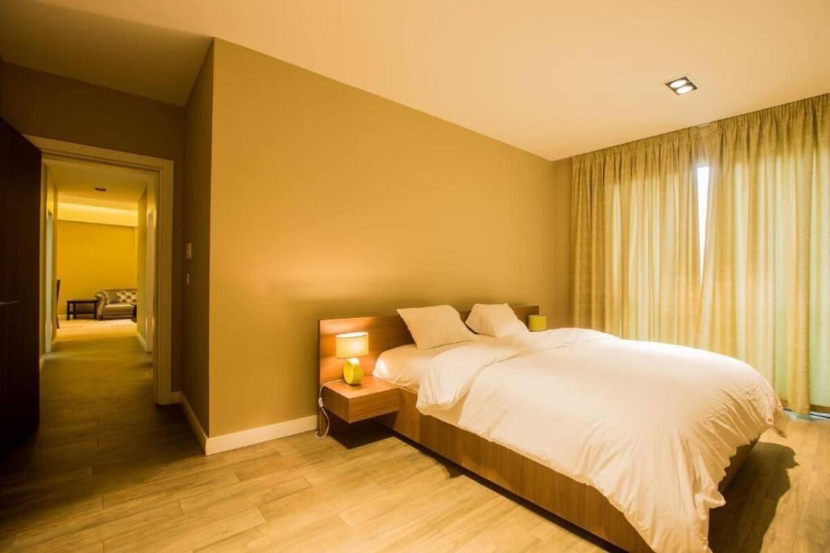 Ein Hotelzimmer mit einem großen Bett, Nachttischlampen und Blick auf einen Flur.