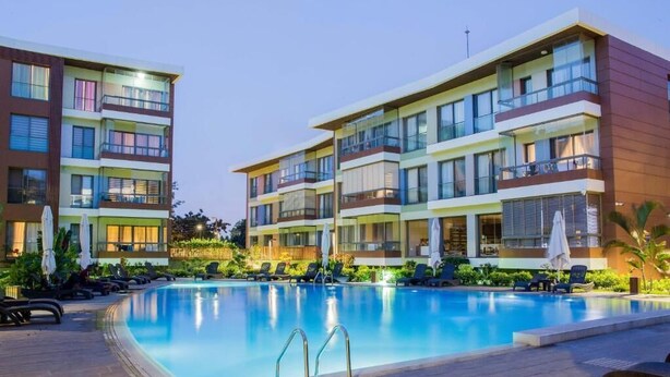 A modern hotel with a swimming pool, multiple balconies, and sun loungers. - Accra Fine Suites  (Accra)