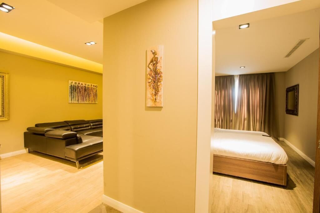A modern hotel room with a sofa set, a bed with a wooden frame, and a wall-mounted artwork.