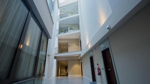 A multi-level interior with a central corridor, glass walls, and a fire extinguisher on the right. - Accra Fine Suites  (Accra)