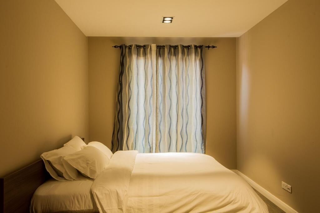 A bedroom with a bed, a window with curtains, and a ceiling light.