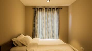 Un dormitorio con cama, ventana con cortinas y una lámpara en el techo.